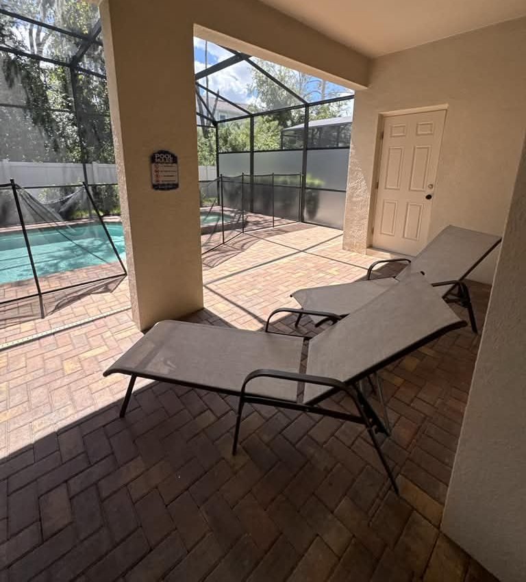 Screened patio with lounge chairs by the pool